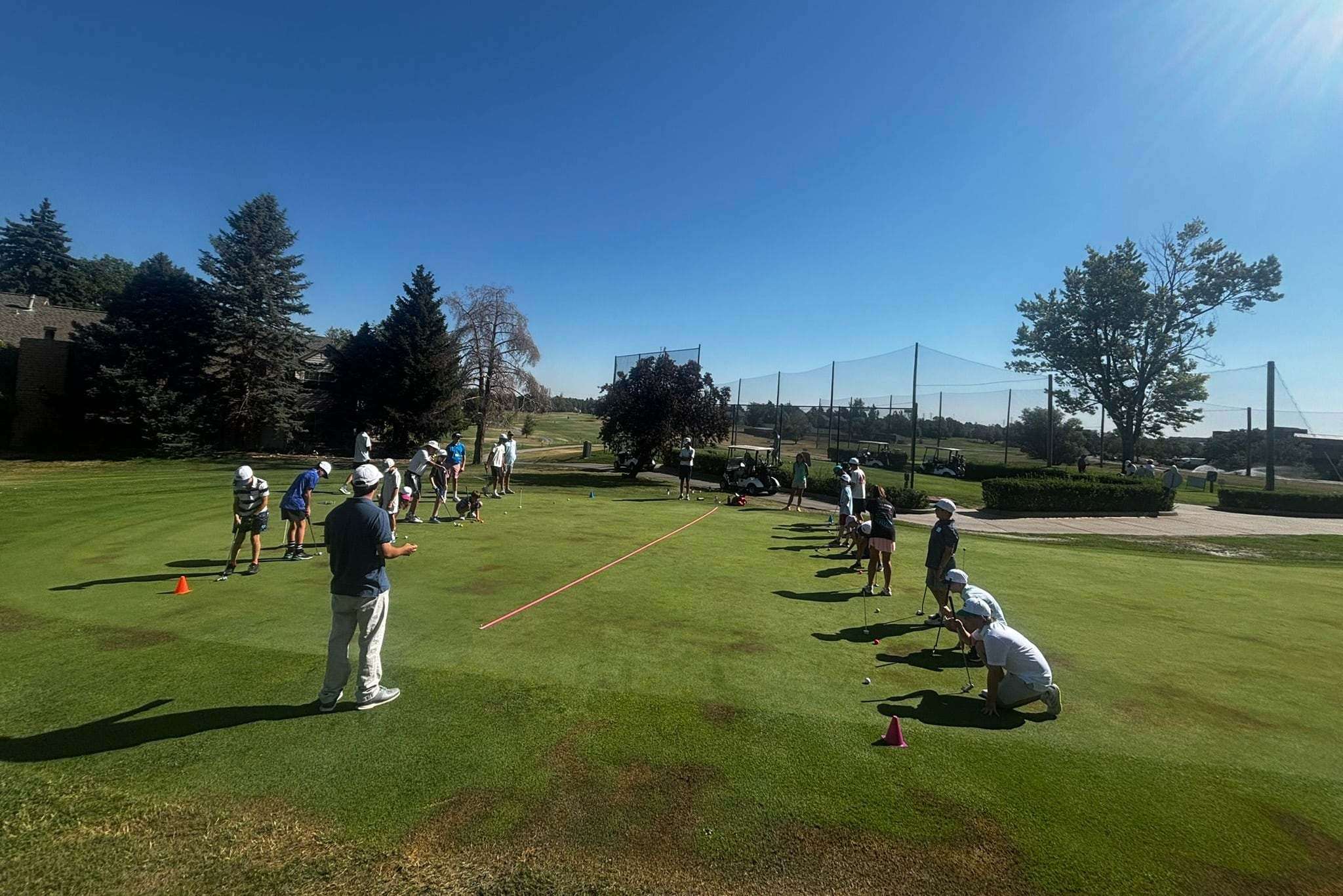 Junior golfers work through putting stations during an outdoor clinic
